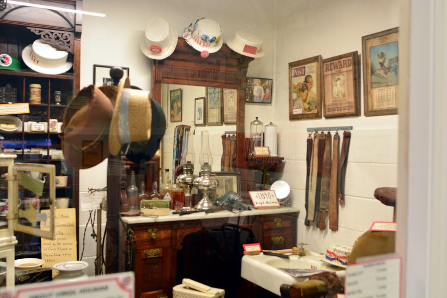 A preserved barbershop display with an old chair, mirror and bottles.