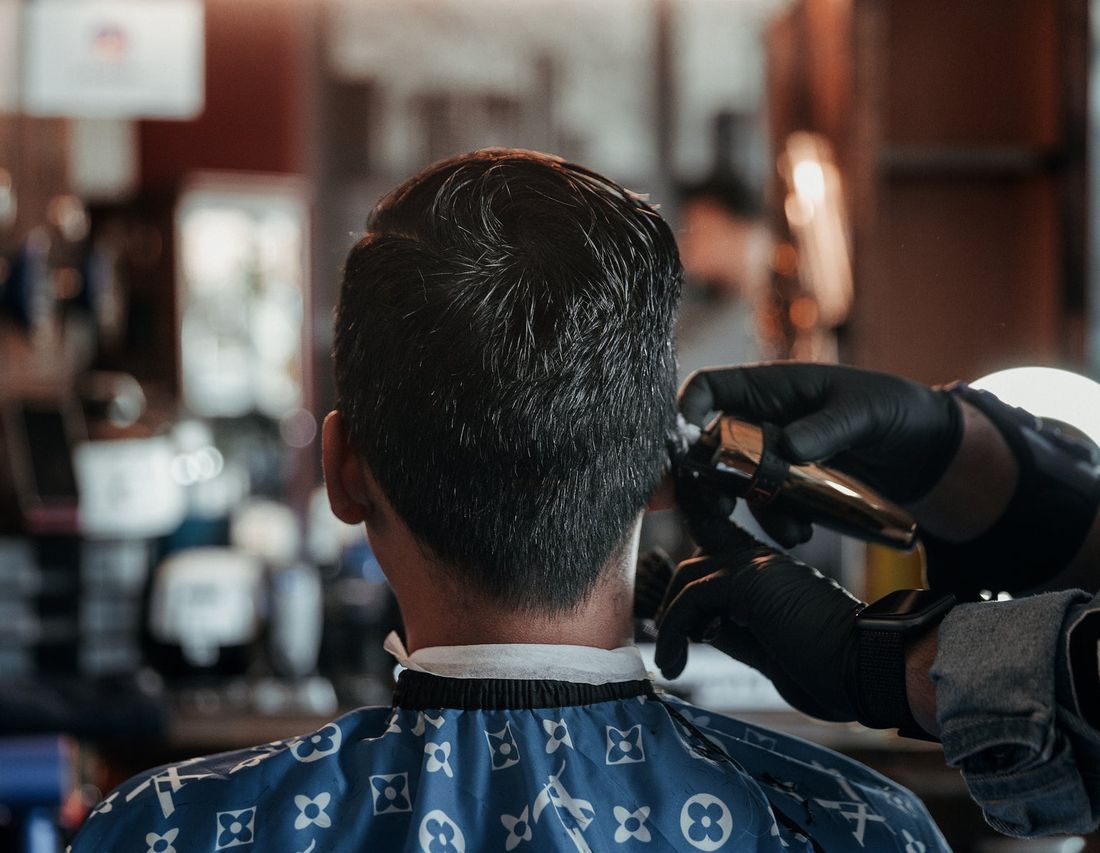 A client in the chair while the barber tidies the back and sides