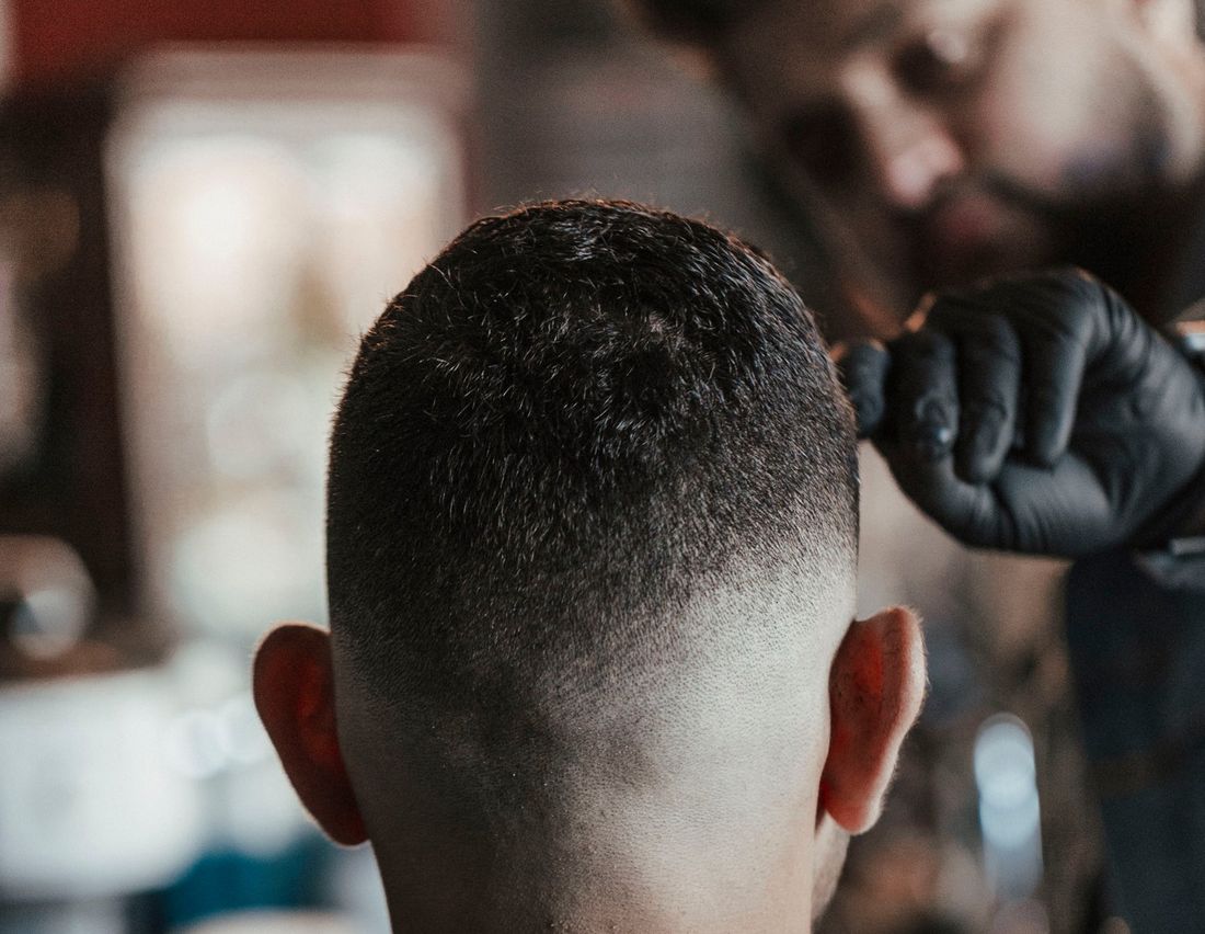 A barber stepping back to check the finished cut