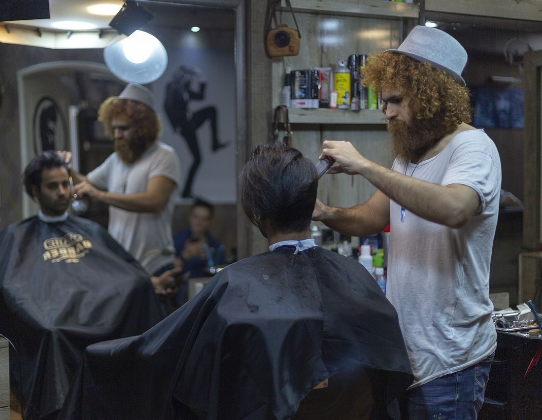 A barber cutting a client&rsquo;s short hair with scissors and comb