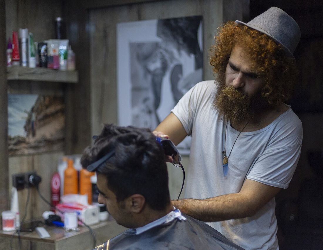 A barber taking clippers to a client&rsquo;s short hair