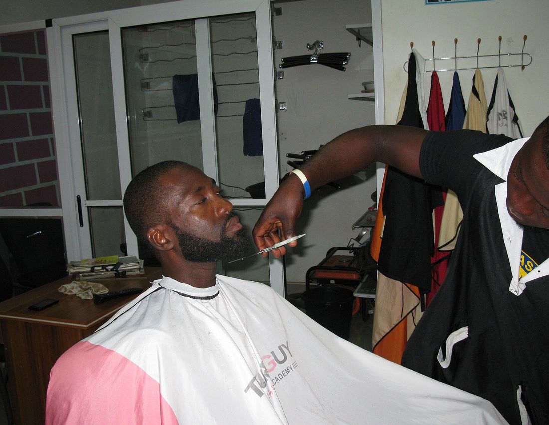 A barber trimming a client&rsquo;s beard with a straight razor
